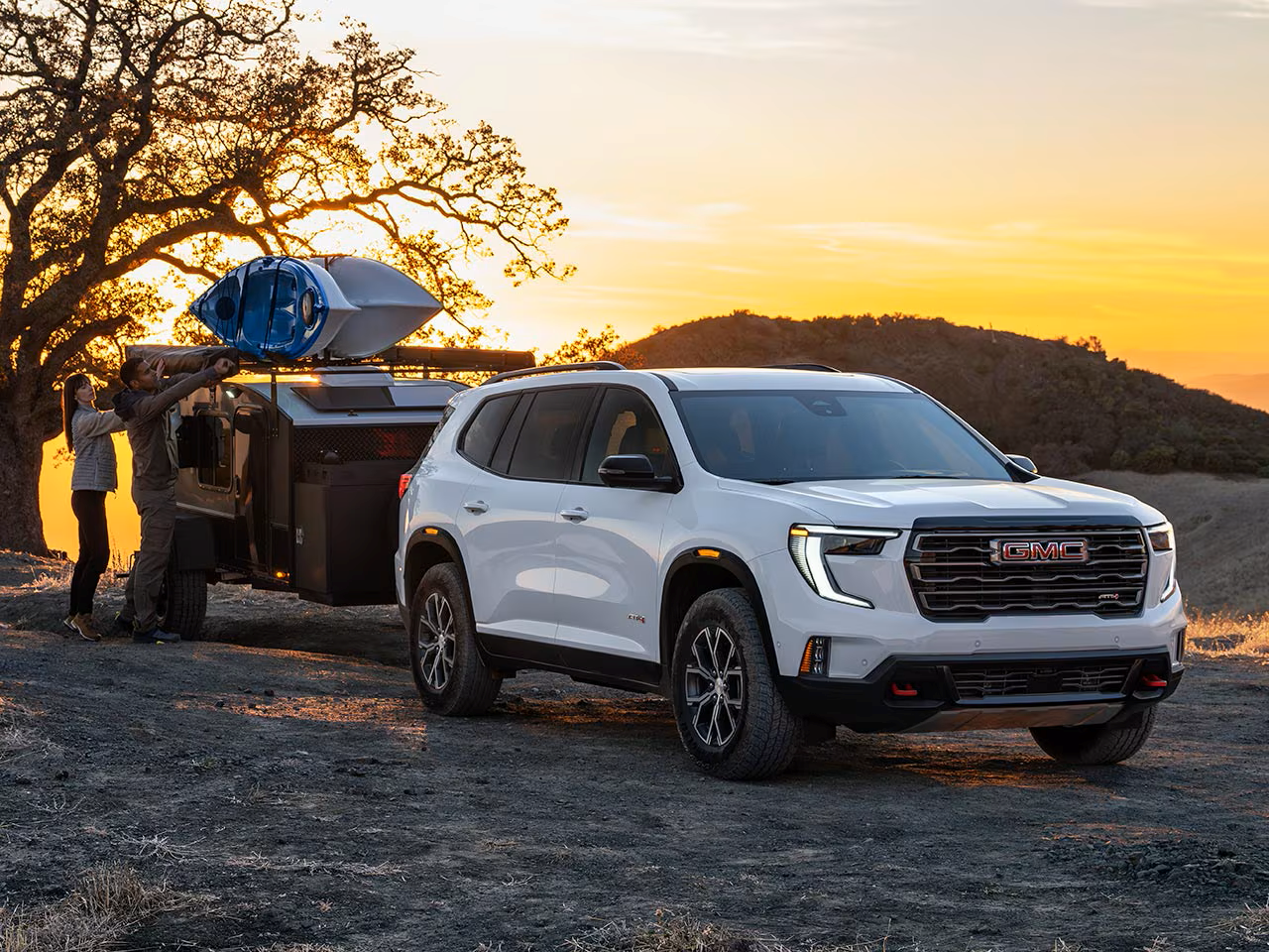 2026 GMC Acadia towing a camper at sunset